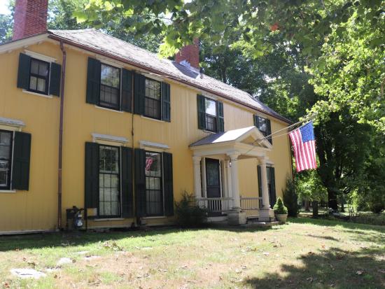 Large yellow two story house with American flag on porch