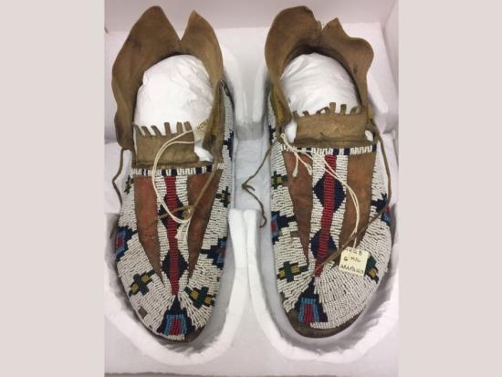 Pair of beaded moccasins sitting side by side in a box.