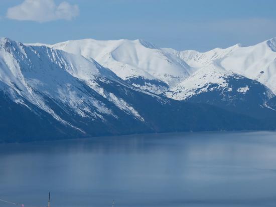White capped mountains are in the background with a bright blue body of water in the foreground. 