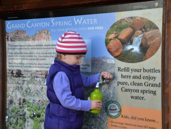 A little girl refills a reusable water bottle at a water filling station