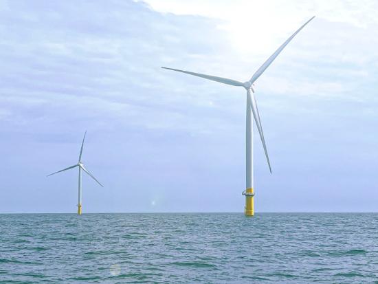 A view of two wind turbines in the ocean