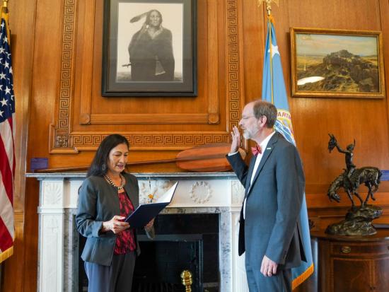 David Applegate raises his right hand as he is sworn in by Secretary of the Interior Deb Haaland