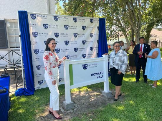 Assistant Secretary Estenoz and others standing in front of sign for Dillard University's Howard Hall. 