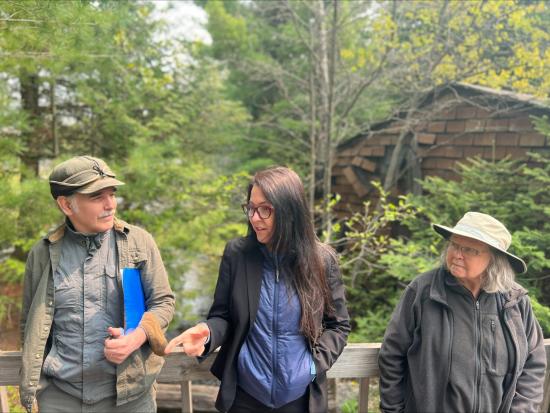 Assistant Secretary Estenoz talking to two people standing on a wooden bridge. 