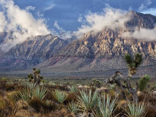 Steep desert mountains with low hanging clouds.