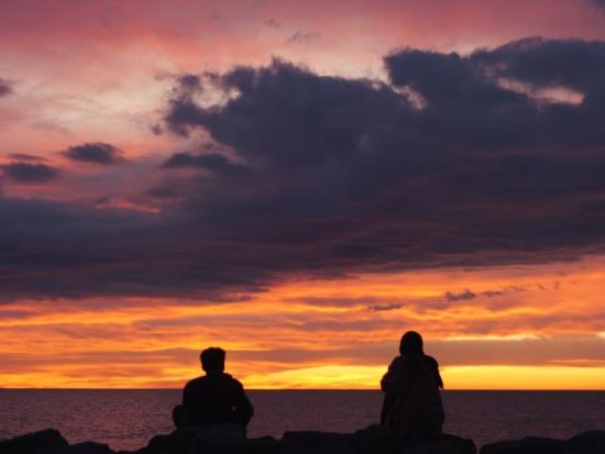 Picture of Couple Sitting on Beach at Sunset