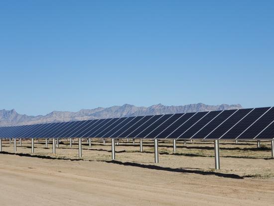 A row of solar panels with a mountain range in the background