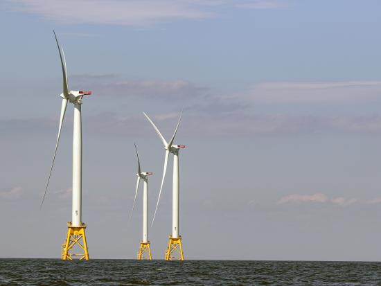 3 distant offshore wind turbines in the water. 