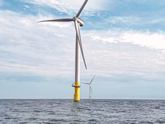 Two wind turbines in the ocean. 