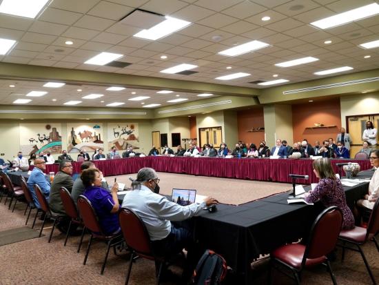 A group of Tribal leaders are seated at a large table
