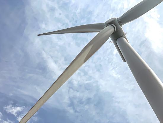 A close-up view of a wind turbine with a partly cloudy sky