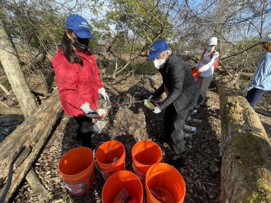Sec Haaland and Dir  Ahuja pick up litter during the Watershed Society Nash Run Trash Trap cleanup. 