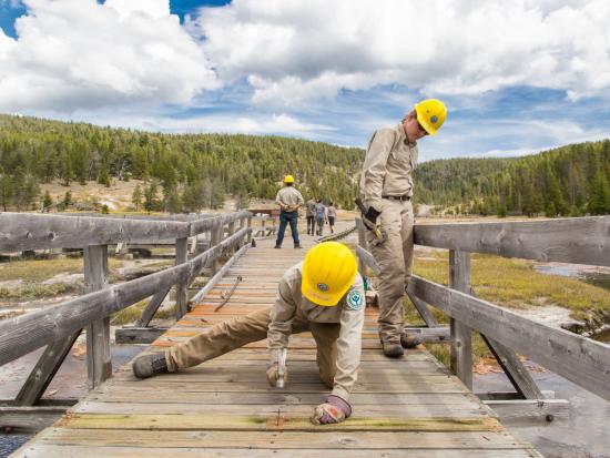 Two crew members repairing a boardwalk.