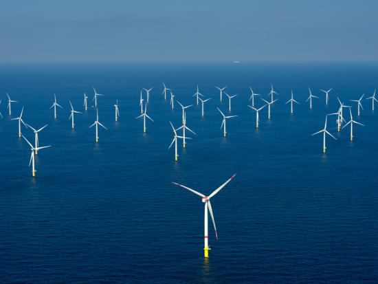 A view of several offshore wind turbines in the ocean.