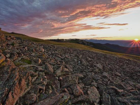 Colorful cloudy sky over rocky mountains.