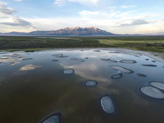 Blue cloudy sky reflected in an area of water in a mountain basin landscape. 