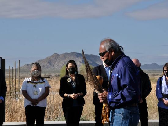 Group of people, including Sec. Haaland, surrounds a person holding feathers 