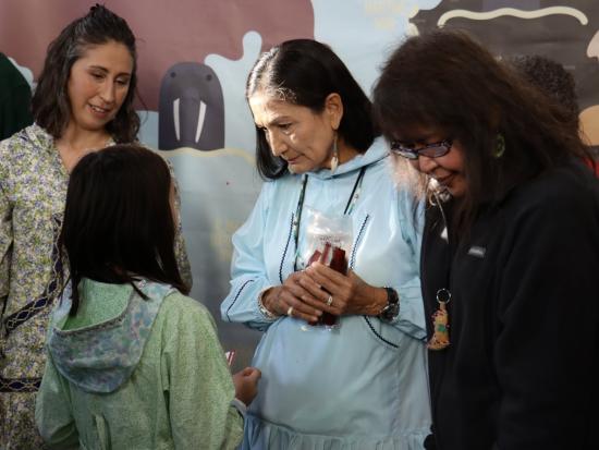 Secretary Haaland and two others having a conversation with a young girl. 