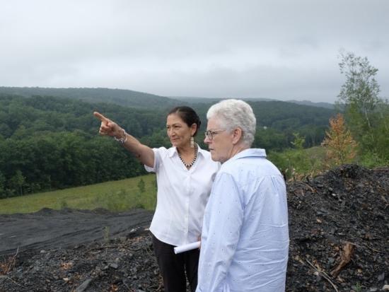 Secretary Haaland points out into the distance and Gina McCarthy follows the gaze. 