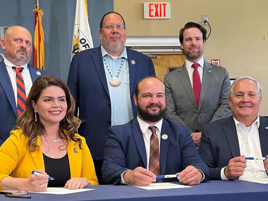 Six people posing for a photo in front of a table with the City of Tucson logo. 