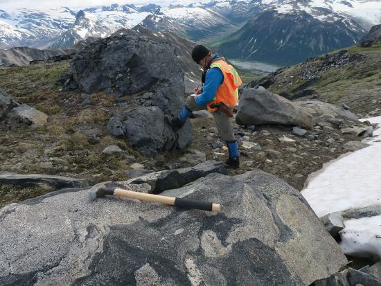 USGS surveyor stands on a rock formation while mapping minerals