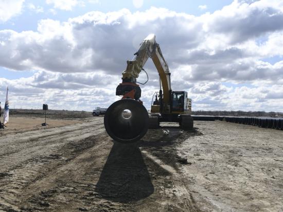 A view of a yellow crane moving a water storage pipe