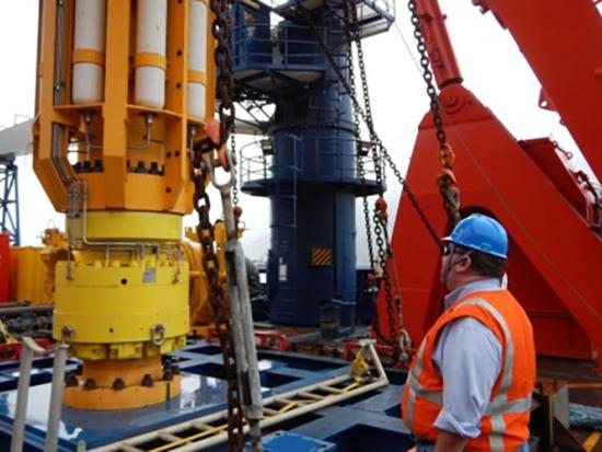 Two people in safety gear inspecting offshore well equipment. 