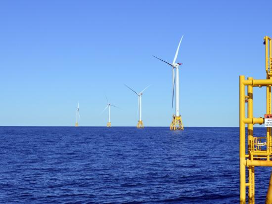 Four distant wind turbines in the ocean. 