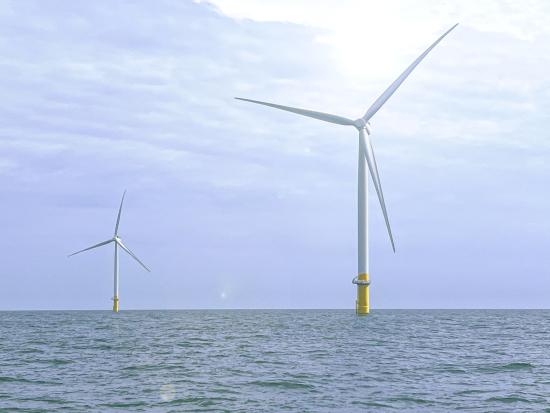 Two offshore wind turbines generating energy in the ocean