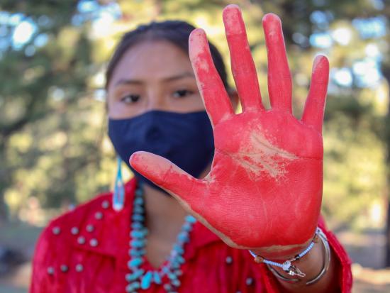 Young woman holds her red-painted palm to the camera