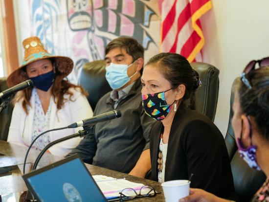 Secretary Haaland speaks into a microphone while wearing a mask.