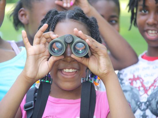 A young girl looks through binoculars
