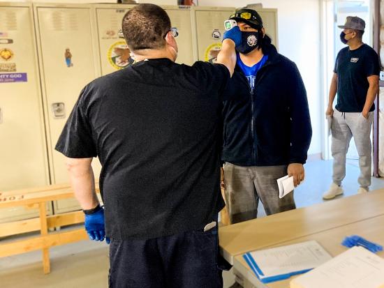 A wildland firefighter's temperature is checked as he checks in to a mobile medical exam clinic. Photo by Holland Foshay, USFWS.