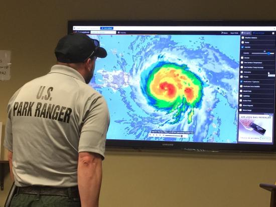 U.S. Park Ranger looks at hurricane footage.