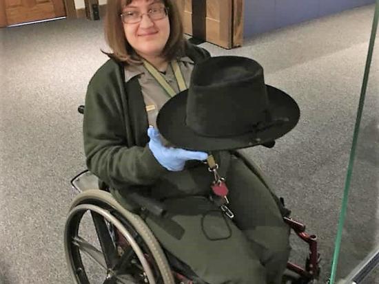 A park ranger in a wheelchair holds an artifact