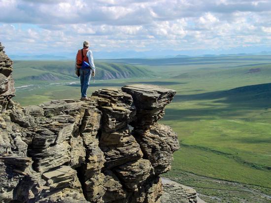 A geologist stands on​ an o​utcrop of Nanushuk Formation, Tuktu Bluff​, Alaska