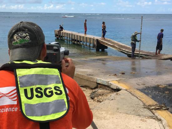 A USGS employee uses equipment to monitor ocean water levels on a beach. 