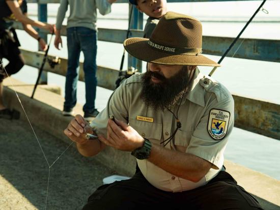 Ranger with a fishing rod and bait.
