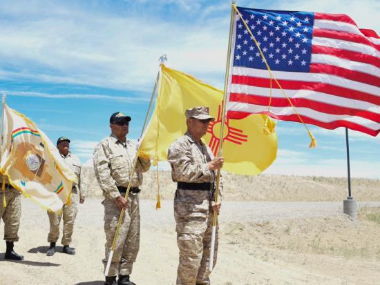 Native men wearing military uniforms hold Tribal and U.S. flags 