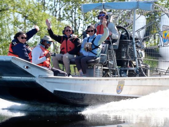 Secretary Haaland and others wave from a speeding airboat crossing Bayou Sauvage 