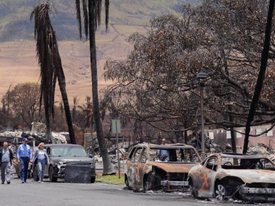 President Biden and First Lady Dr. Jill Biden walk past burned-out cars on a street in Lahaina