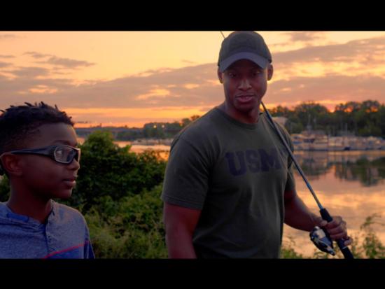 African American man with fishing pole walks beside African American teen