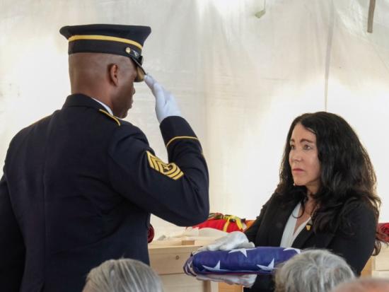 Soldier presents woman with flag