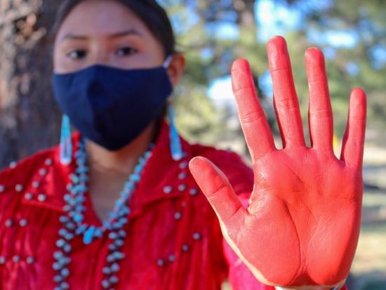 Native woman holding up her red-painted hand