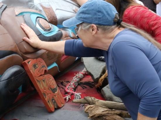 woman touches totem pole