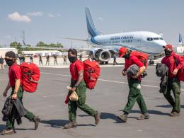 Firefighters carry their gear away from a plane