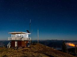 The Spot Mountain Lookout seen at night, the Indian Ridge Fire burning in the distance. Photo by Mark Moak, FS.