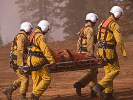 Four medics in yellow flight suits and helmets carrying a stretcher 