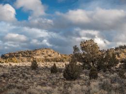 High desert landscape with sagebrush and cloudy blue sky. 