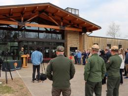The Park Superintendent addresses a crowd of people from a podium in front of the renovated Mammoth Cave Lodge